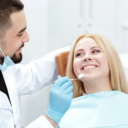 A young woman smiling while the dentist’s checks her smile