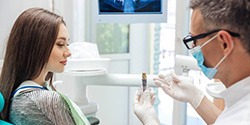 Dentist showing woman an implant model