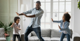 parent dancing with their children in their living room