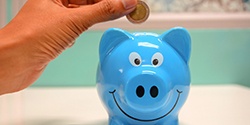 Hand putting coin in blue piggy bank