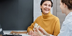 Woman in yellow sweater smiling at dentist at consultation