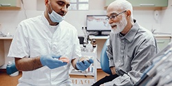 An older man talking to his dentist about dentures