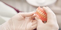 Gloved hands holding a pair of dentures