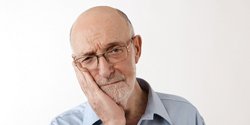 Frowning older man with a failed dental implant in Denton