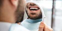 Man smiling at this reflection in dental mirror