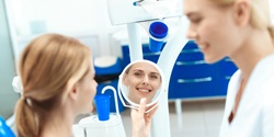 A female patient looking at her smile while the dentist looks on nearby