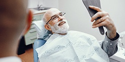 dental implant patient admiring his new smile in a mirror