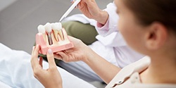 dentist showing a dental implant model to a patient