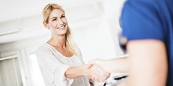A woman shaking hands with a dental employee.