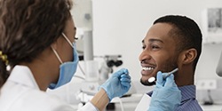 young man sitting in dental chair and smiling at his dentist 