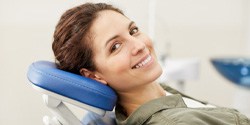 Woman smiling in dental chair after teeth whitening in Denton, TX