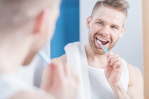 man smiling brushing his teeth