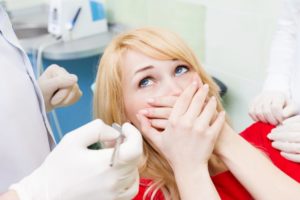 Nervous woman covers mouth before tooth extraction in Denton