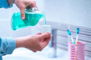 dentist in Denton pouring green mouthwash into white lid 