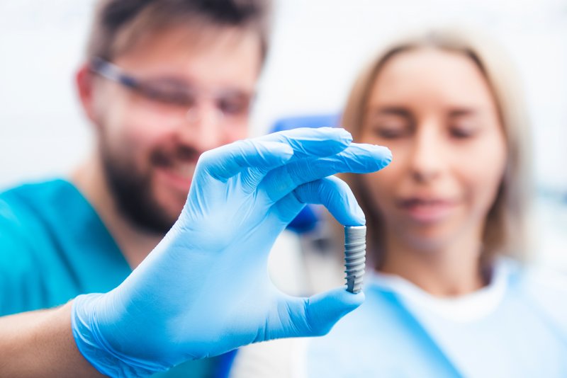 Dentist and patient looking at model of dental implant