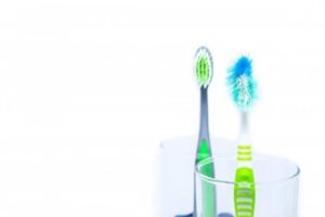 A new toothbrush and a used toothbrush in a glass