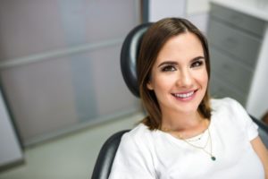 Woman smiling in dental chair while looking at dentist