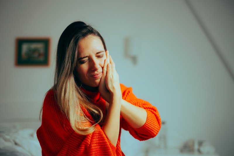 a woman holding her cheek due to a dental emergency