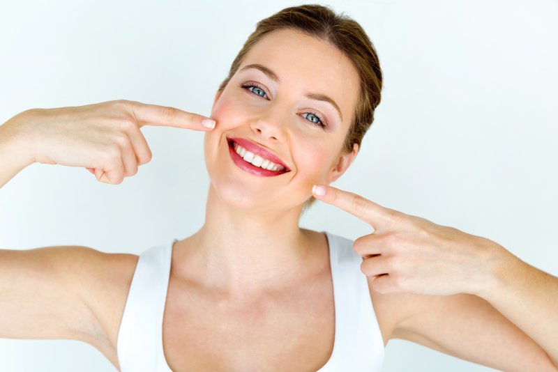 young woman pointing to her whiter smile